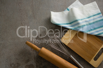 Rolling pin, whisker, chopping board and cloth on table