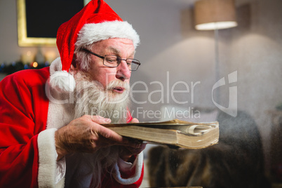 Santa Claus blowing dust from book