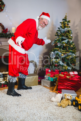 Santa claus showing christmas tree at home