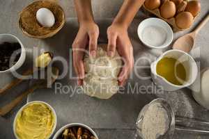 Woman preparing dough surrounded with various ingredients