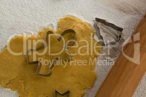 Gingerbread dough with flour, cookie cutter and rolling pin on wooden table