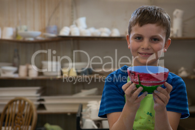 Boy holding a panted pot in pottery workshop