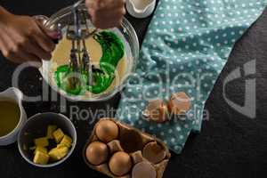 Woman whisking batter after adding green food color