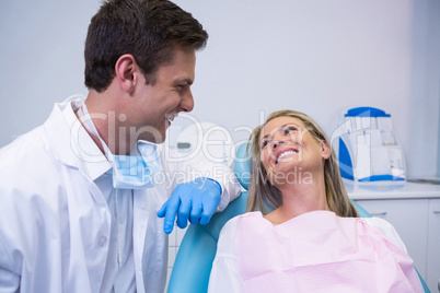 Smiling patient looking at dentist while sitting on chair