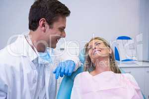 Smiling patient looking at dentist while sitting on chair