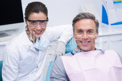 Smiling dentist by patient at medical clinic
