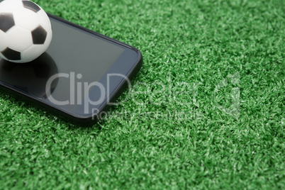 Football and mobile phone on artificial grass