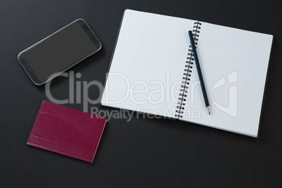 Passport, mobile phone, pencil and organizer on black background