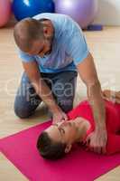 Yoga instructor guiding student in exercising at health club