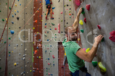 Portrait of male athlete climbing wall in health club