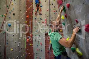 Portrait of male athlete climbing wall in health club