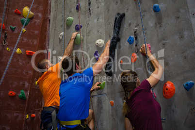 Athletes and trainer climbing wall in gym