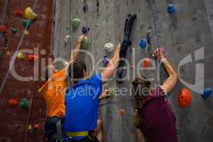 Athletes and trainer climbing wall in gym
