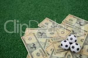 Footballs and currency notes on artificial grass