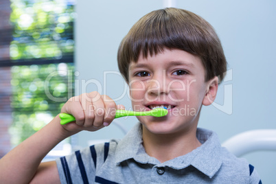 Boy holding toothbrush while sitting on chair at medical clinic