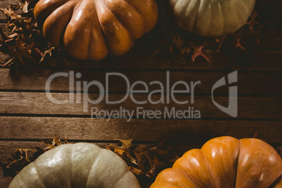 Autumn leaves by pumpkins on wooden table