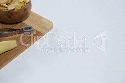 High angle view of peeler and fresh ginger on wooden cutting board