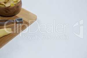 High angle view of peeler and fresh ginger on wooden cutting board