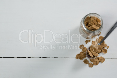 Wheat flakes in glass jar and spoon