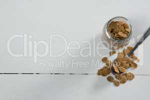 Wheat flakes in glass jar and spoon