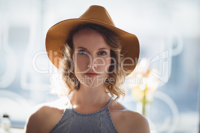 Portrait of confident young woman wearing hat at coffee shop