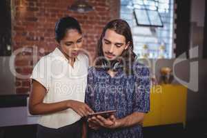 Young man showing tablet computer to female friend at coffee shop