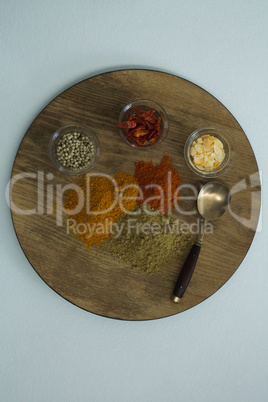 Various spices on wooden board with spoon