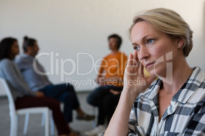 Worried woman with head in hand while friends discussing in background