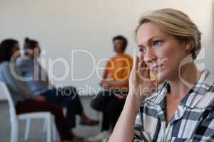 Worried woman with head in hand while friends discussing in background