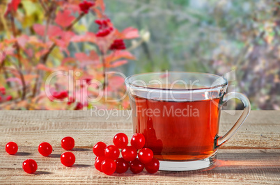 Tea with viburnum berries on wooden table