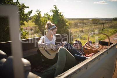 Woman playing guitar while man listening in a car