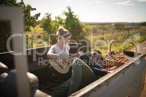 Woman playing guitar while man listening in a car