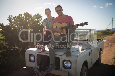 Man playing guitar while woman having a drink