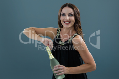 Smiling woman opening bottle of champagne