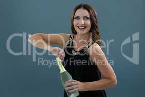 Smiling woman opening bottle of champagne