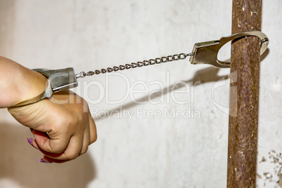 Hand with handcuffs tied to pipe