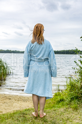 Young woman with bathrobe at the lake