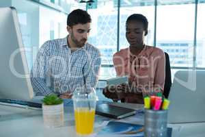Executives discussing over digital tablet at desk