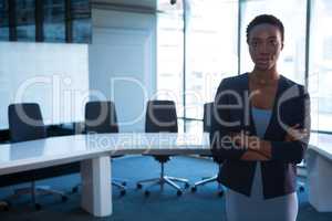 Female executive standing with arms crossed in boardroom