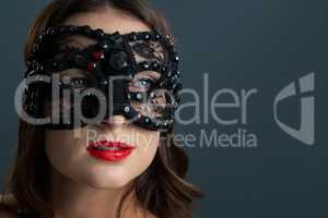 Woman wearing masquerade mask against black background