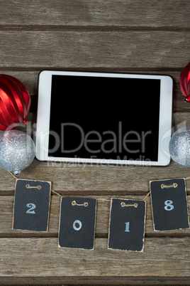 Baubles and cards forming 2018 around the digital tablet