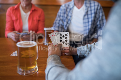 Friends playing cards while having glass of beer