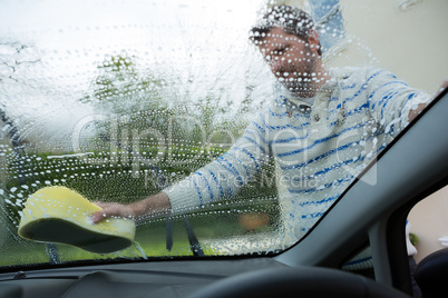 Auto service staff washing a windscreen with sponge