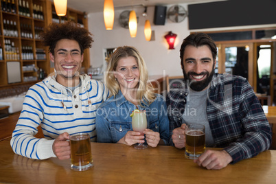 Friends having glass of drinks at counter in restaurant