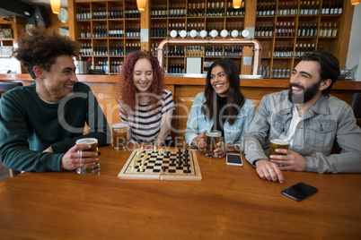 Friends playing chess while having glass of beer in bar