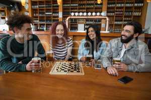 Friends playing chess while having glass of beer in bar
