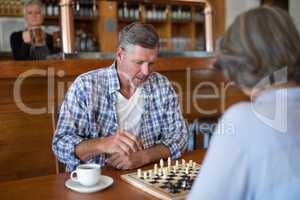 Friends playing chess while having coffee