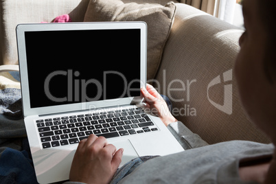 Woman using laptop on sofa in living room