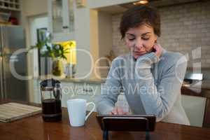 Woman using digital tablet in kitchen