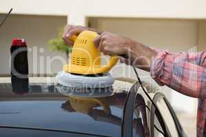 Auto service staff cleaning a car with rotating wash brush